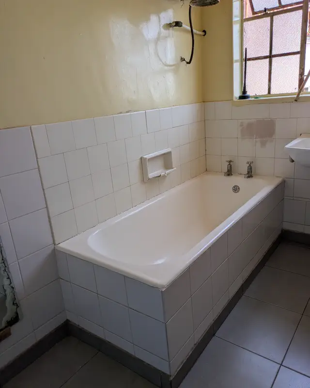 A tiled bathroom with a bath and a window