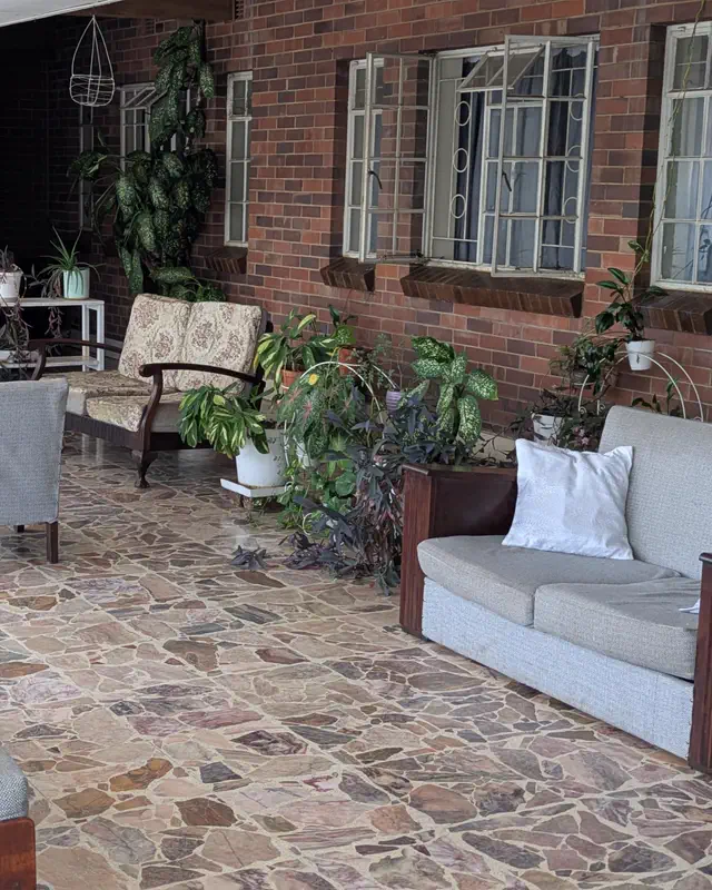 The veranda, with sofas, plants and a red-brick wall