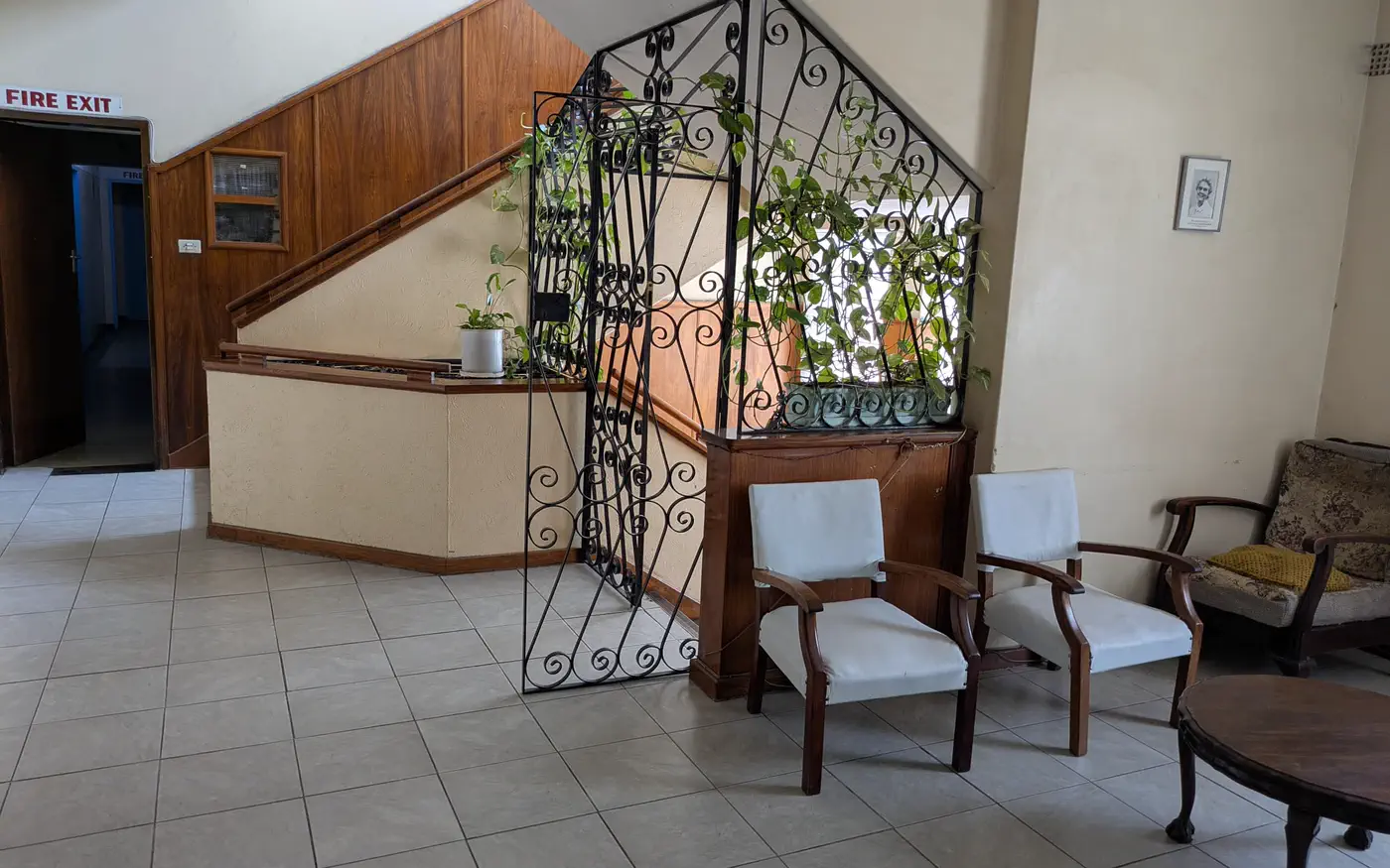 The front hall, with a wrought-iron screen, pot plants and armchairs by the stairs